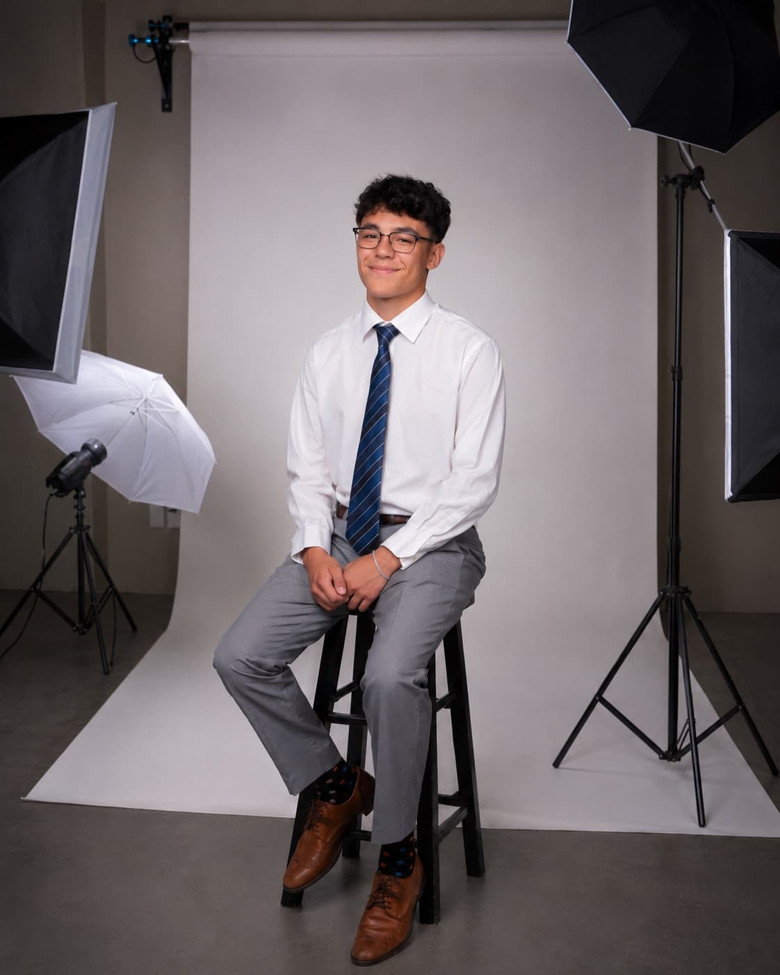 Evan, founder of Veo Studios, seated on a stool between studio lights